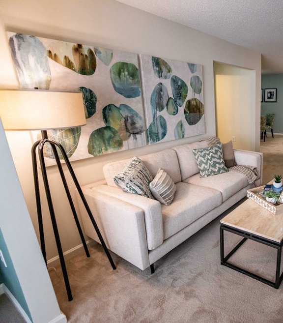 A living room with a white couch and a lamp.