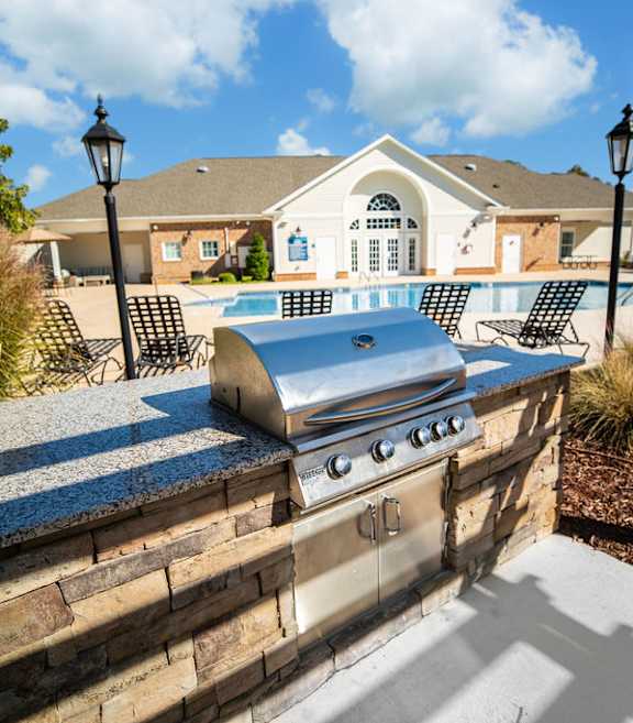 A backyard with a stone wall and a grill.