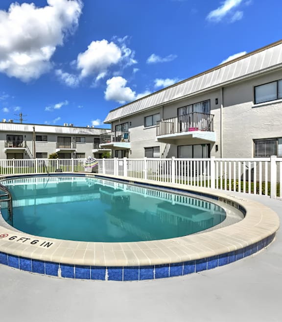 A swimming pool in a residential area with buildings in the background.