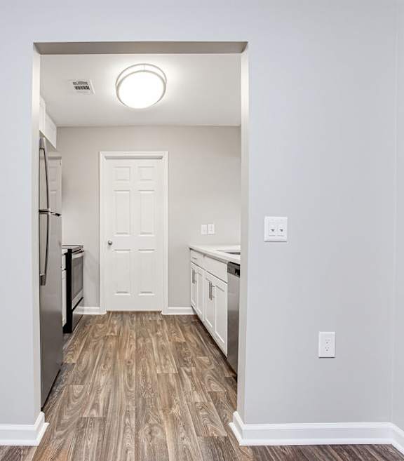 a renovated living room and kitchen with white walls and wood floors