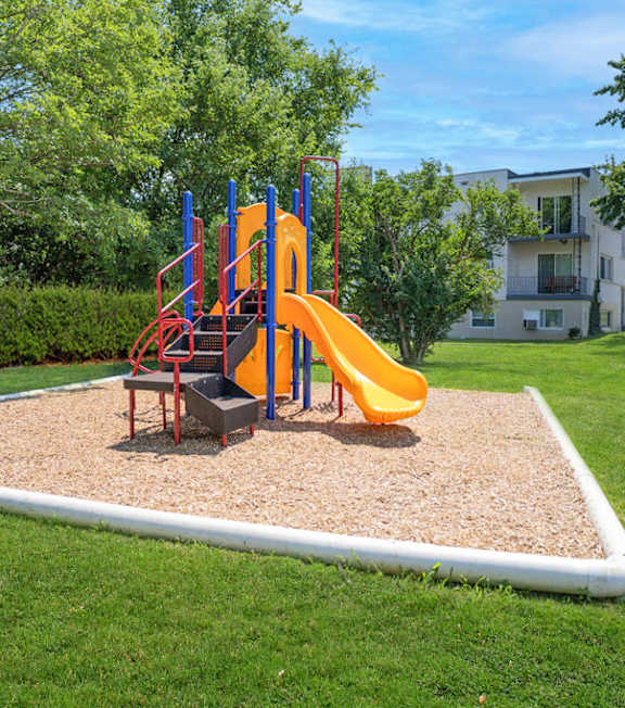 A playground with a yellow slide and a red and blue structure.