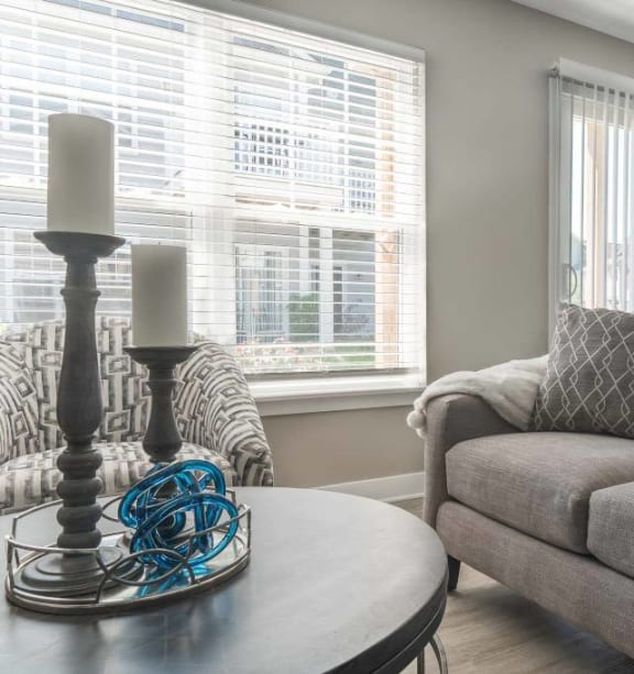 View of great room living area with couch, coffee table & chair. Beyond the couch are the sliding doors to the private patio and the dining area