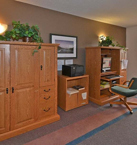 A room with a wooden cabinet, a chair, and a small plant on top of the cabinet.