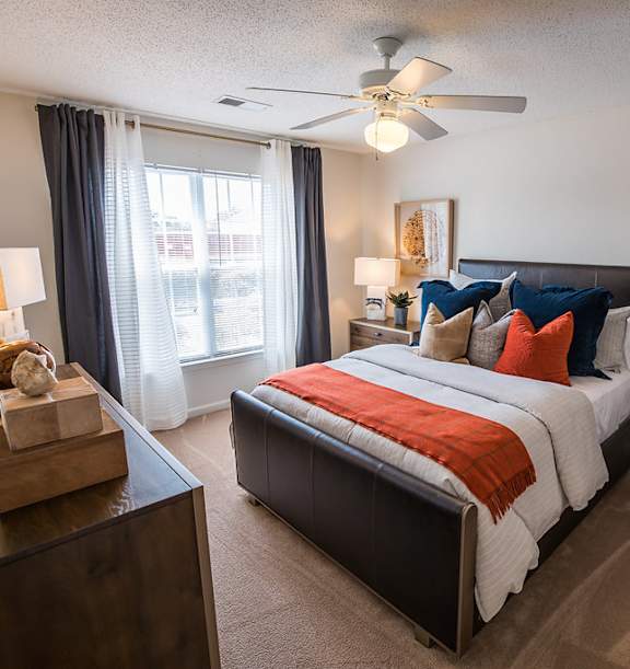 A bedroom with a bed, chair, and a ceiling fan.