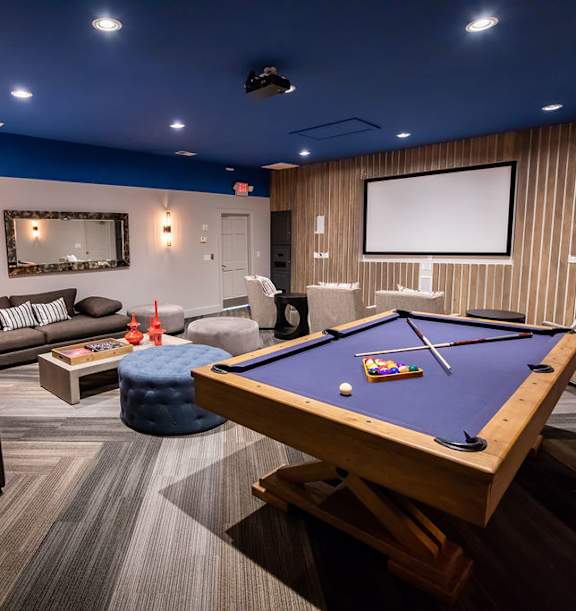 A pool table is in the middle of a room with a couch, a coffee table, and a television.