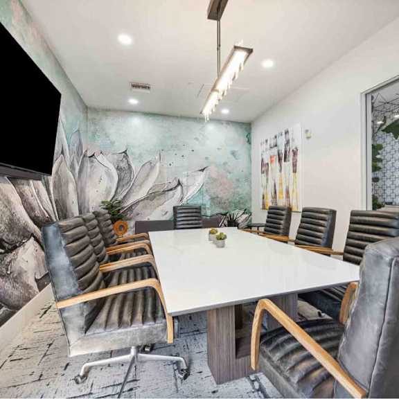 A conference room with a large table surrounded by chairs.