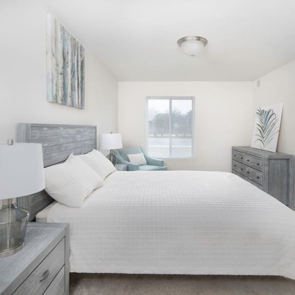 a white bedroom with a large bed and a window