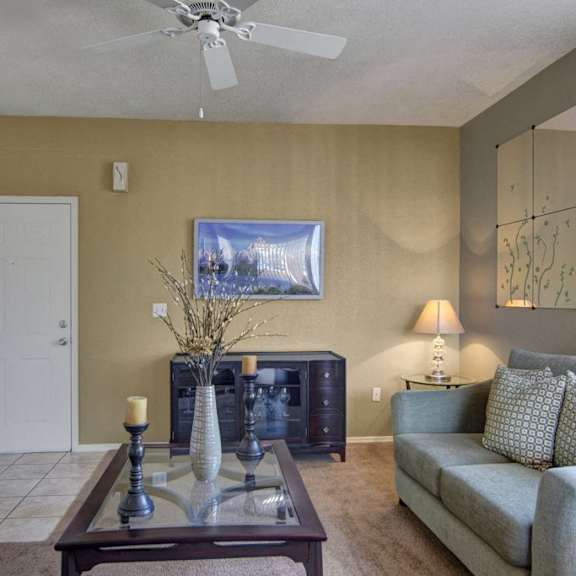 The living room at an Arezzo apartment, complete with a couch, coffee table, vase, candles, and artwork. 