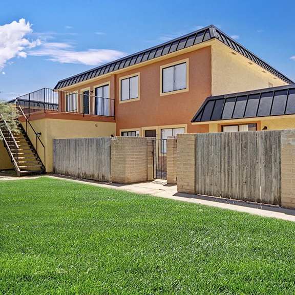The view of an Avanti Townhome from the exterior with orange and yellow walls, and green space in front of it. 
