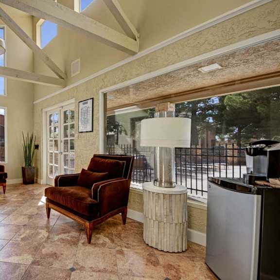 The community room, with plush chairs, vases, coffee tables, a coffee maker, and a mini refrigerator. 