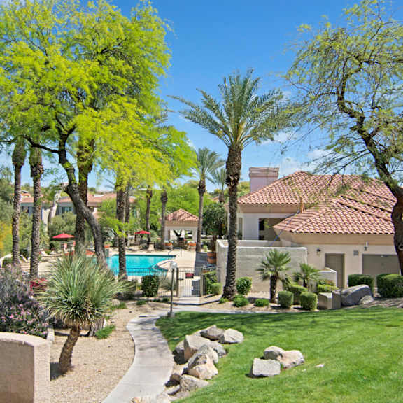 The outdoor area with a lawn and a pool, surrounded by trees at Mirador Apartments. 