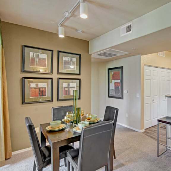 A dining room and kitchen with a table and chairs and a barstool counter at Natura Villas Apartment Homes. 