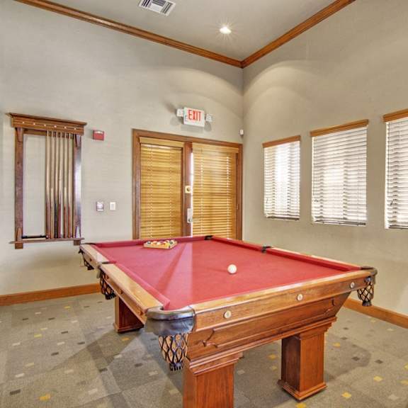 A clubhouse at Paradise Falls with a pool table, windows, and a table and chairs. 