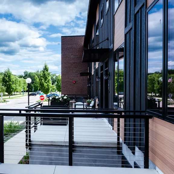 A balcony with a railing overlooks a parking lot and trees.