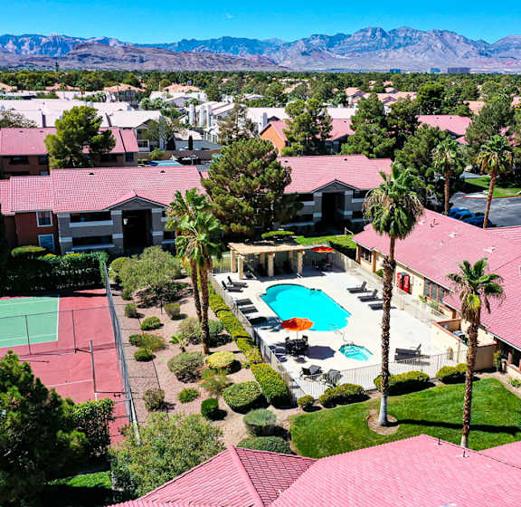 A view of a tennis court and pool surrounded by houses.