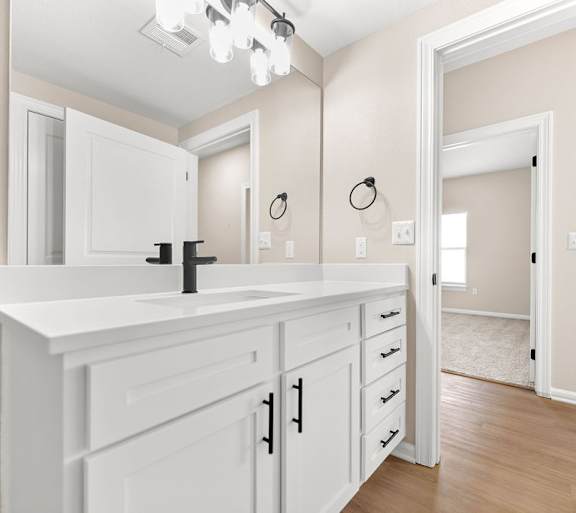 A bathroom with a white vanity and a mirror above it.