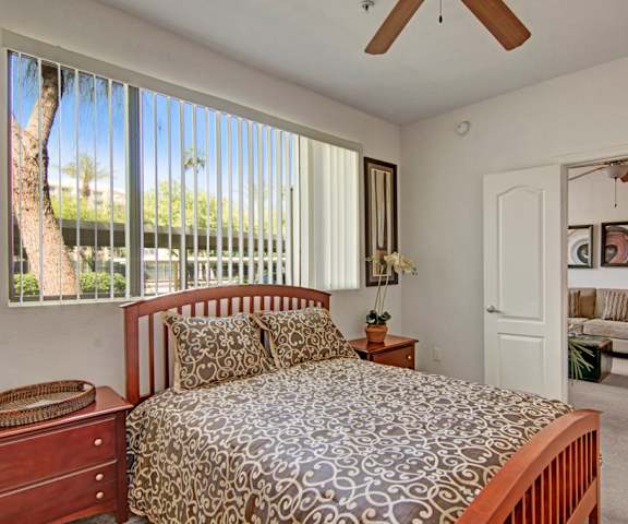 A bedroom with a bed, a ceiling fan, and a large window at Acclaim. 
