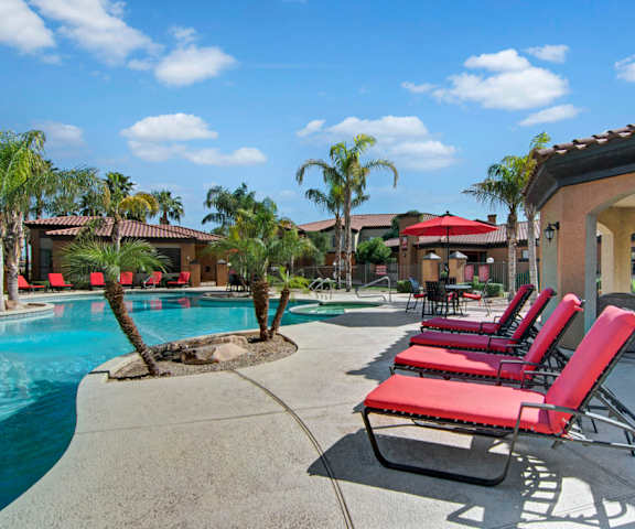A resort-style pool with red chaise lounges and palm trees at Arezzo.