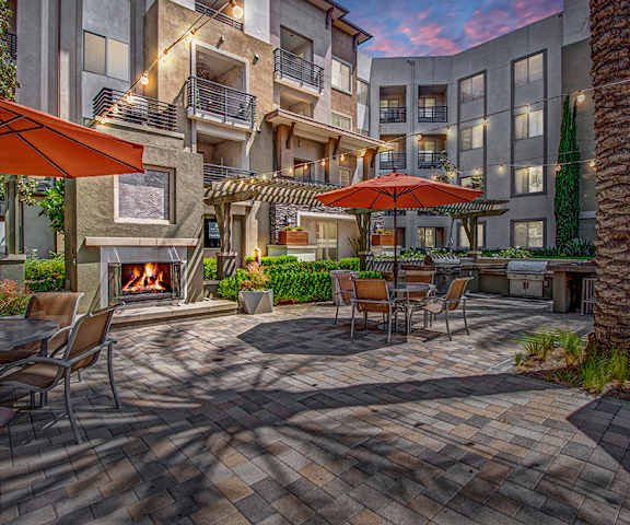 A patio with a fireplace and tables with umbrellas at Artisan at Main Street Metro. 