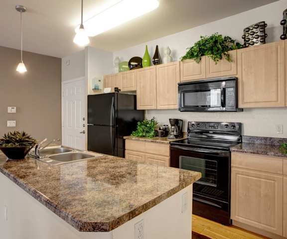 A kitchen with a granite counter top and black appliances at Aspire Pinnacle Peak. 