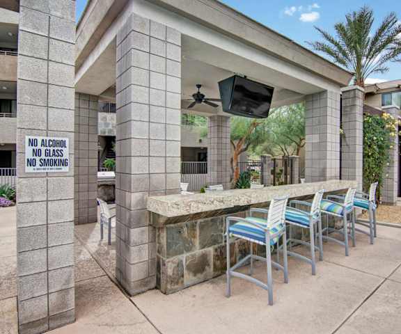 A patio with a table and chairs and a television at Aspire Pinnacle Peak. 