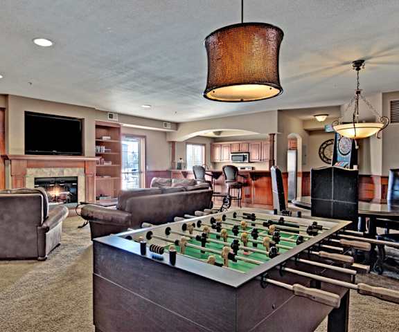 A resident lounge with a fireplace, TV, bookshelves, tables, chairs, games, and a pool table at Grand River Estates. 