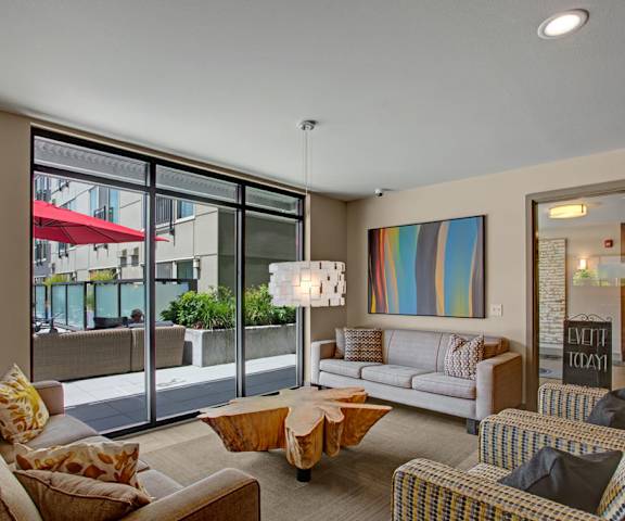 The resident lounge with a fireplace, couches, decorations, plush chairs, coffee tables, and a view of the pool area at Leilani Apartment Homes. 