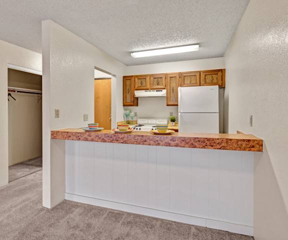 A cozy kitchen with white appliances, a light counter with lots of room, and spacious wooden cabinets at Park Plaza Apartments. 