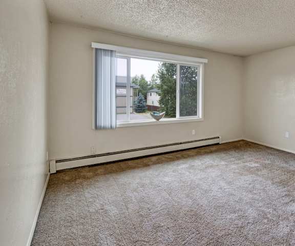 An empty carpeted bedroom with a window at Rancho Tudor Apartments. 