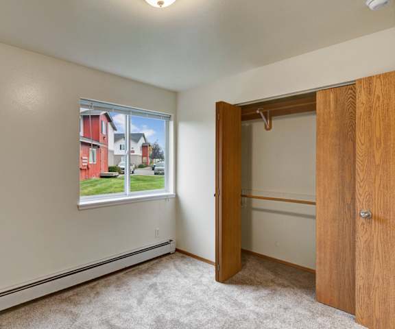 A large, empty carpeted bedroom with overhead lighting and a closet at Strawberry Lane Apartment Homes. 