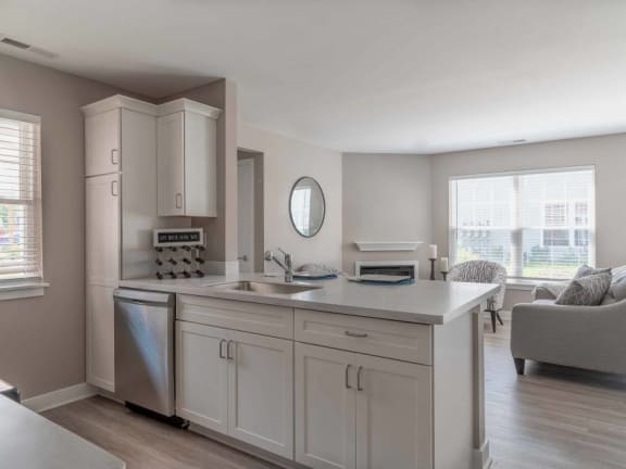 View of apartment kitchen with pantry, dishwasher, breakfast bar overlooking the great room living and dining areas