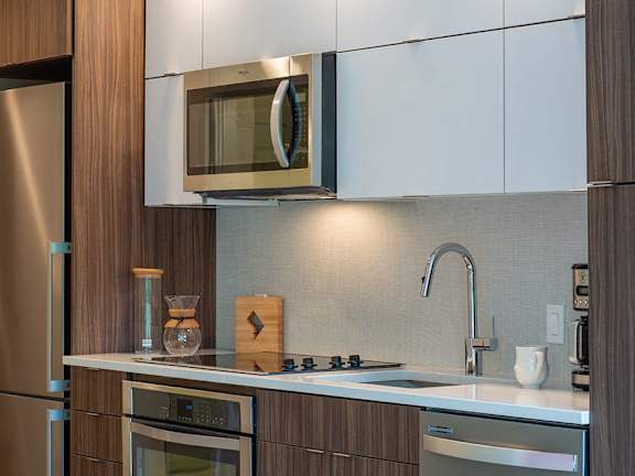 A modern kitchen with a stainless steel refrigerator and wooden cabinets.