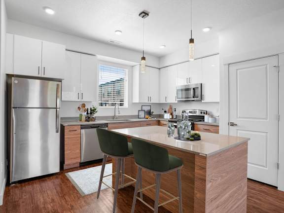 A modern kitchen with a wooden island and green barstools.