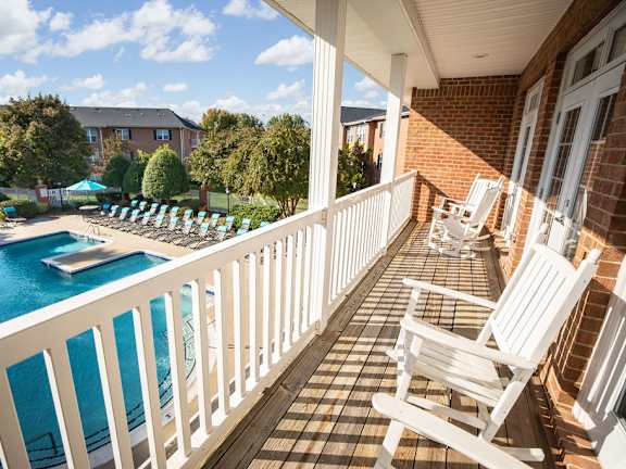 A pool area with white chairs and a white railing.