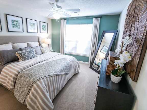 A bedroom with a large bed and a ceiling fan.