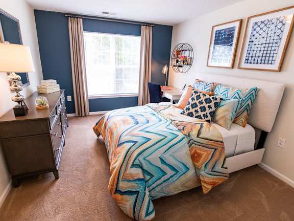 A bedroom with a bed, nightstand, and window.