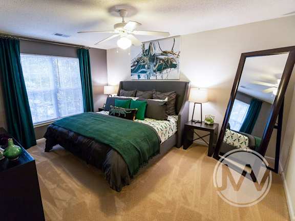 A bedroom with a large bed and a ceiling fan.