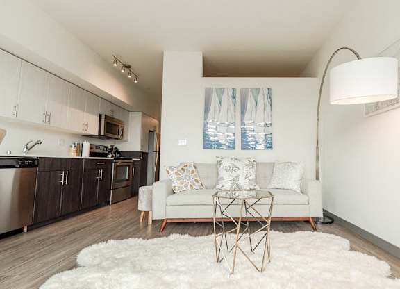 Apartments in Seattle, WA - Icon Apartments Modern Living Room Next to Kitchen with Hardwood Flooring and Natural Light at Icon Apartments, Washington