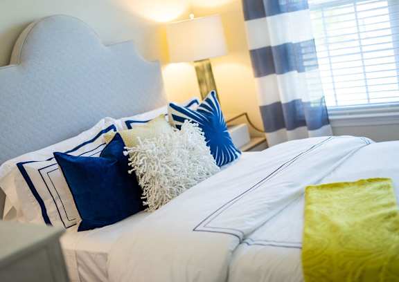 A bed with white sheets and blue and white pillows.