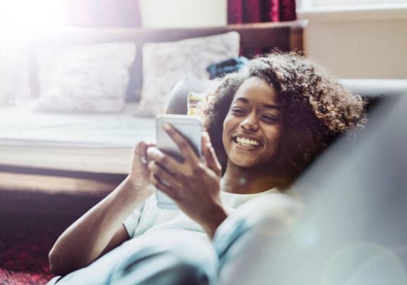 a woman laying on a bed laughing while looking at her cell phone