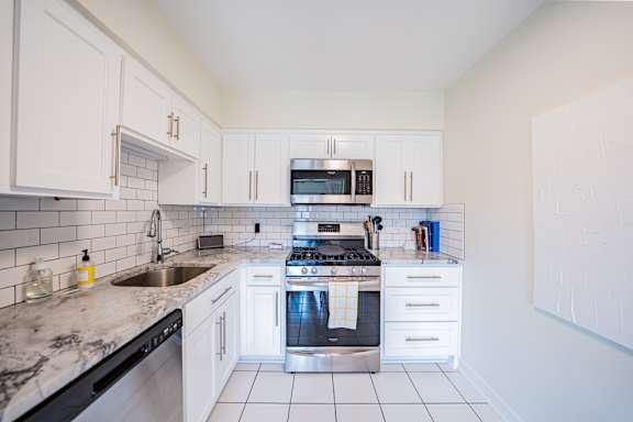 A kitchen with white cabinets and a black dishwasher.