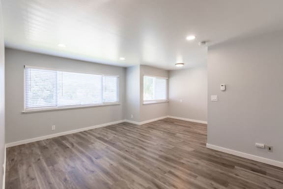 an empty living room with a large window and wood flooring