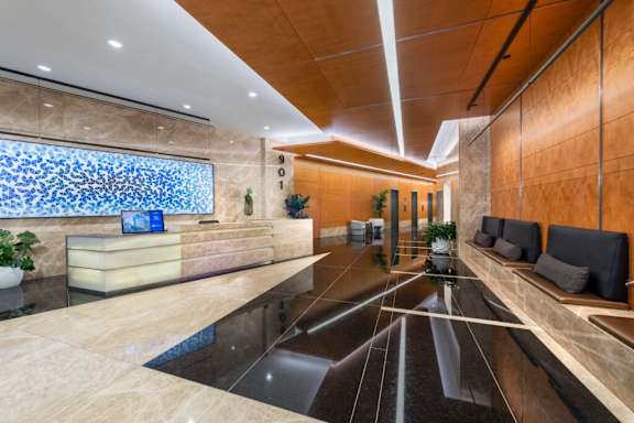 A reception area with a blue glass wall and a wooden bench.