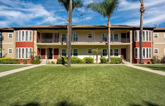 A row of apartment buildings with a green lawn in front.