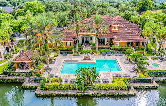 A swimming pool surrounded by a brick patio and palm trees.