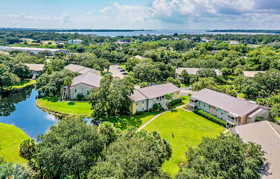 A bird's eye view of a residential area with houses surrounded by greenery and a body of water.