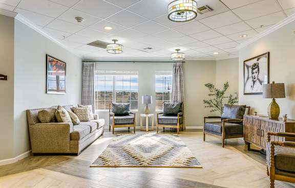 A well-lit living room with a grey sofa, a wooden coffee table, and a rug on the floor.