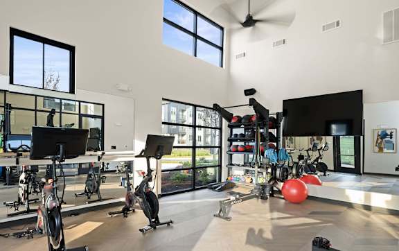 A gym with exercise equipment and a fan.