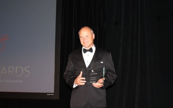 a man in a suit and bow tie holding an award