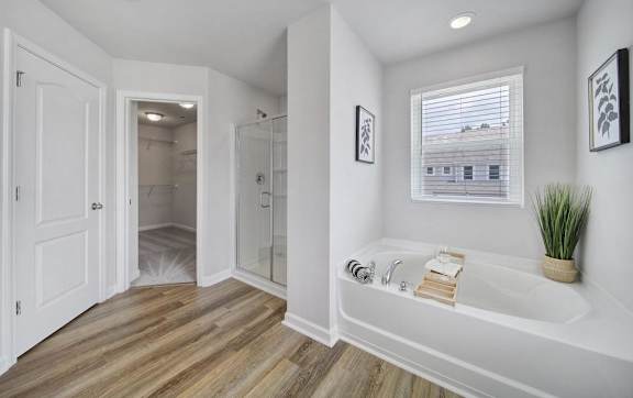A white bathroom with a large tub and a window.